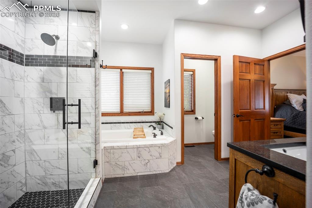 Image 24 of 48: Bathroom with heated floors, vanity, a shower stall, a garden tub, and rece
