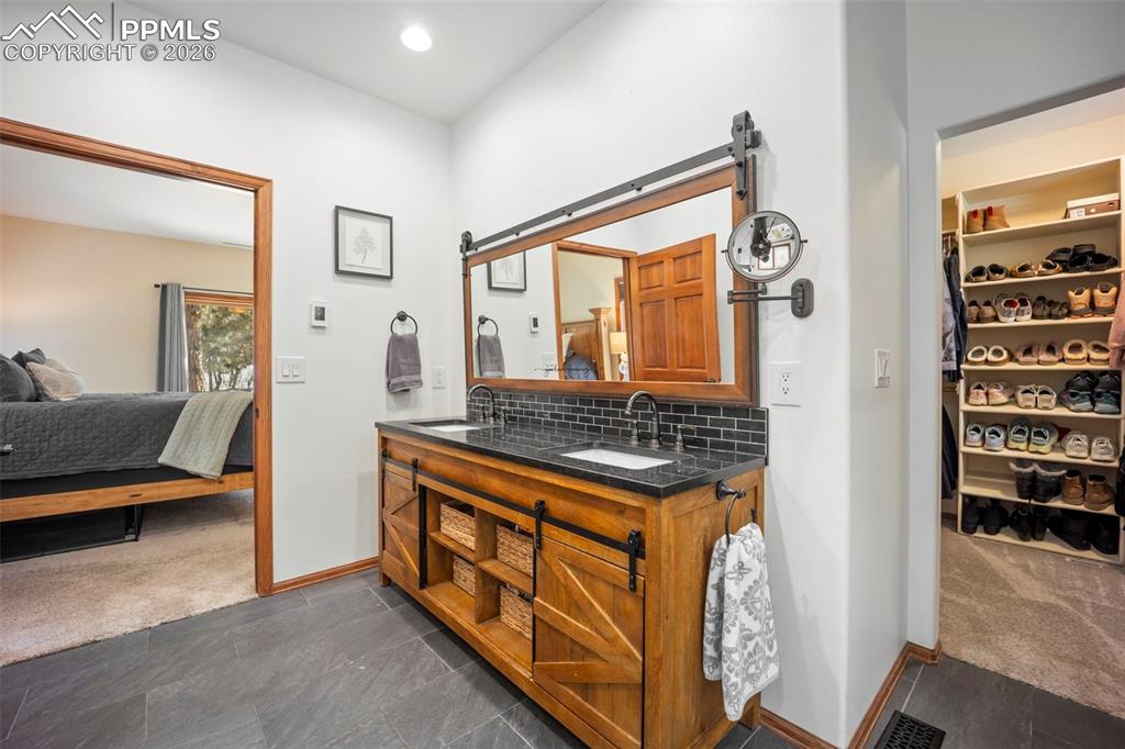 Image 25 of 48: Ensuite bathroom with heated floor, a spacious closet, dark carpet, double 