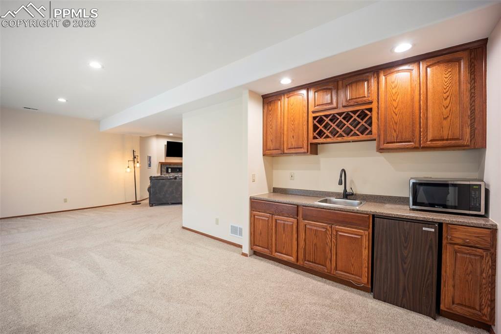 Image 30 of 48: Indoor wet bar featuring brown cabinetry, dishwashing machine, recessed lig