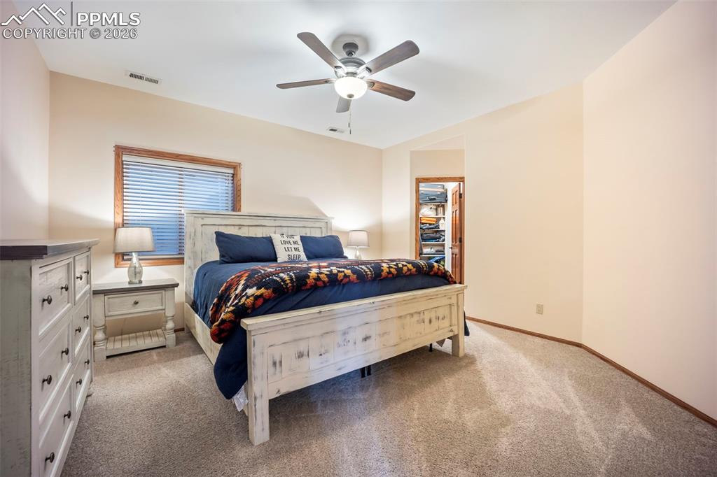 Image 32 of 48: Bedroom featuring a spacious closet, light colored carpet, and ceiling fan