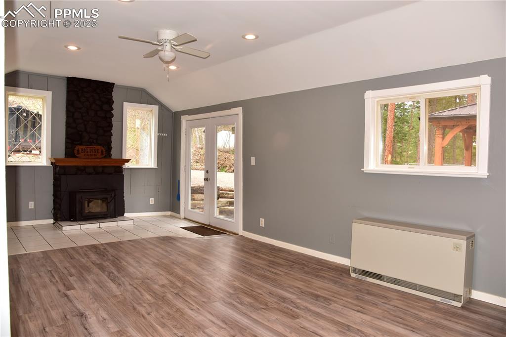 Image 10 of 46: Unfurnished living room with radiator, ceiling fan, vaulted ceiling, wood f