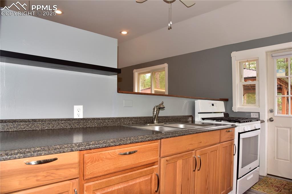 Image 12 of 46: Kitchen with white gas range oven, a sink, healthy amount of natural light,