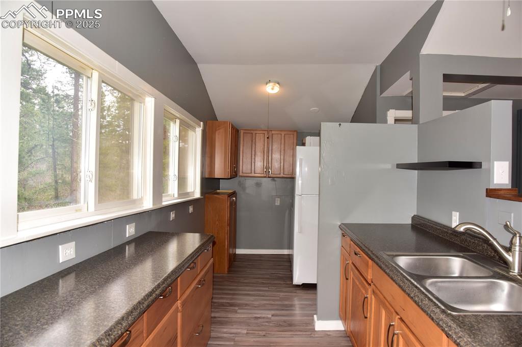 Image 14 of 46: Kitchen featuring a sink, freestanding refrigerator, dark countertops, dark