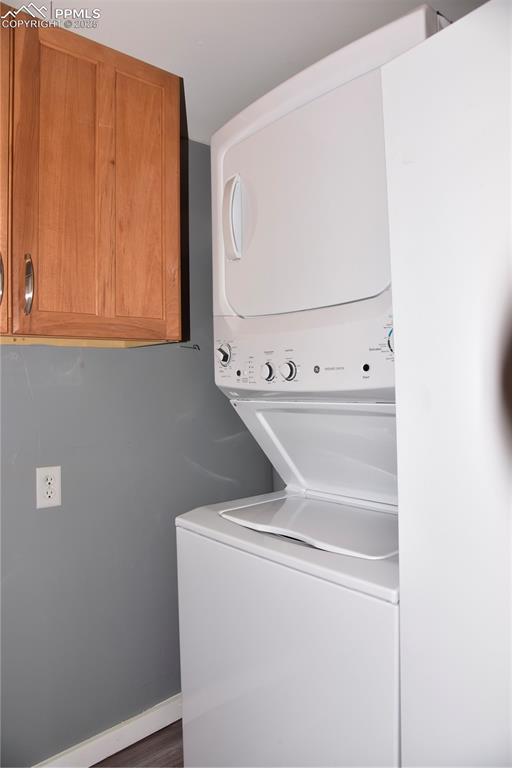 Image 16 of 46: Washroom featuring stacked washer / drying machine and cabinet space