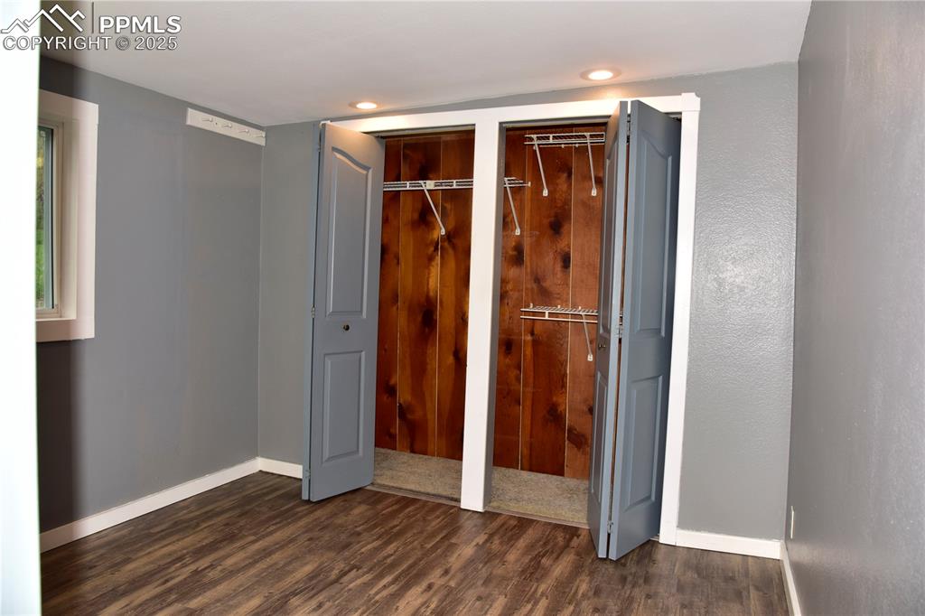 Image 24 of 46: Unfurnished bedroom with dark wood-style floors, two closets, baseboards, a