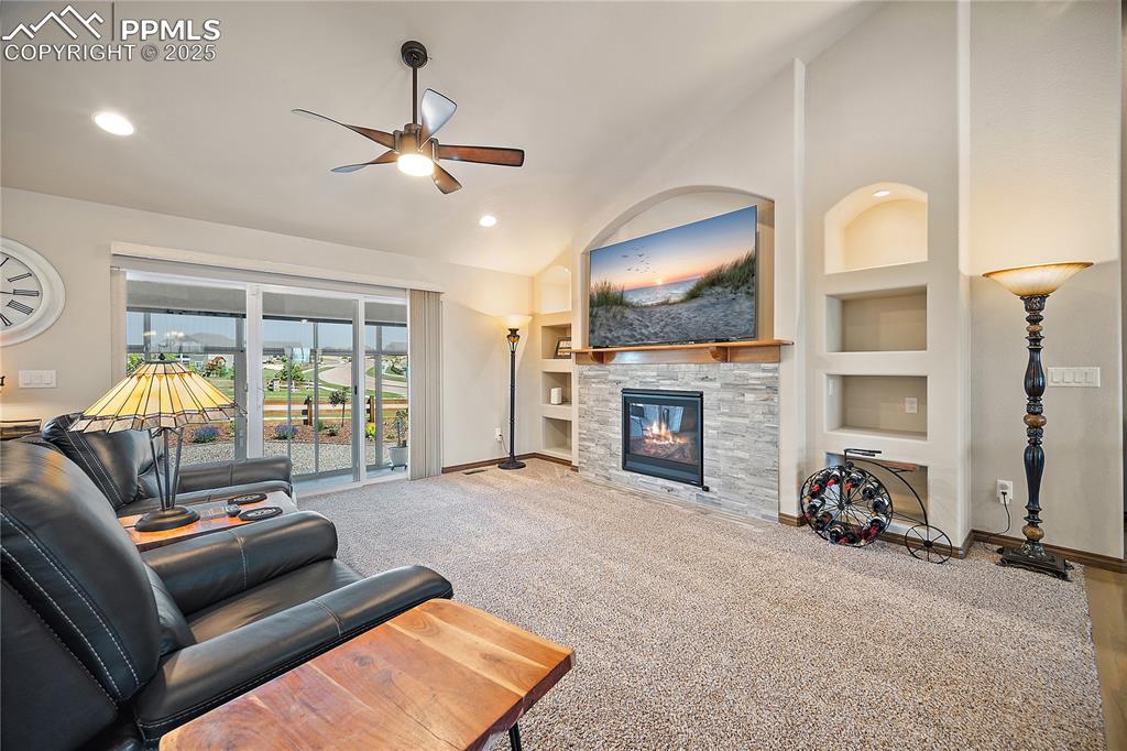 Image 5 of 50: Main level living room with arched built-ins, gas fireplace with stone surr