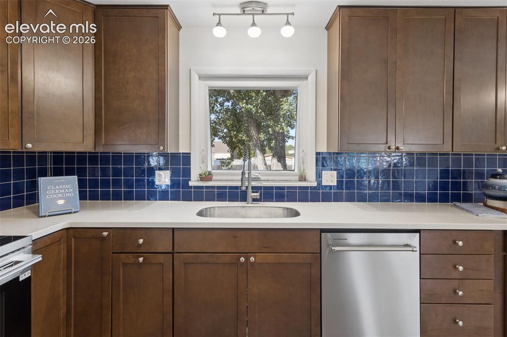 Image 12 of 50: Wood-finish cabinetry, stainless steel dishwasher, undermount sink, and rec