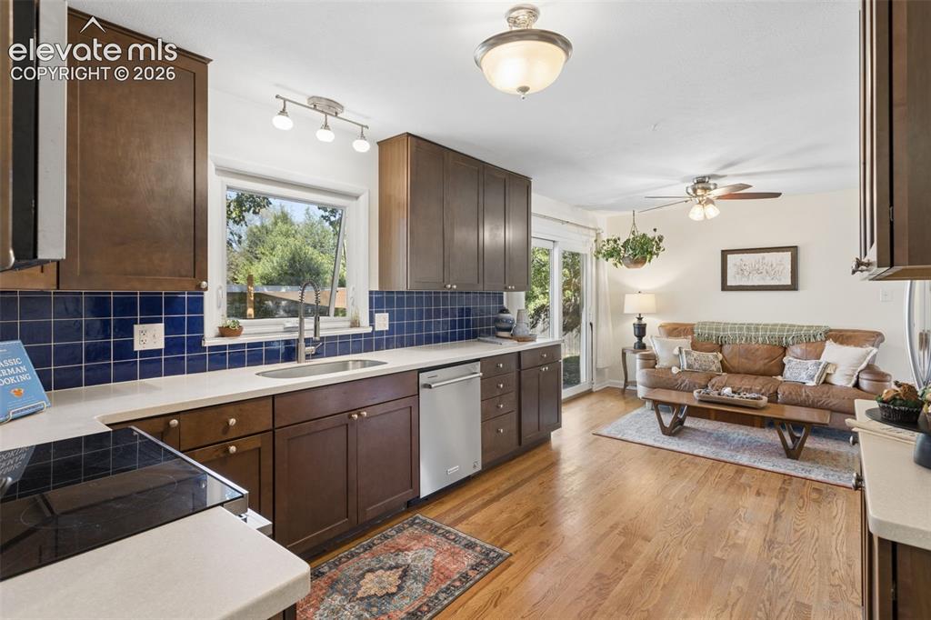 Image 13 of 50: Kitchen featuring wood-finish cabinetry, stainless steel sink, tile backspl