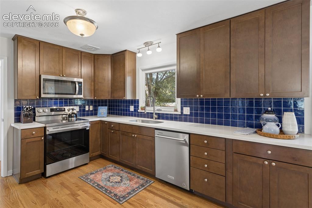 Image 15 of 50: Kitchen featuring wood-finish cabinetry, stainless steel appliances, white 
