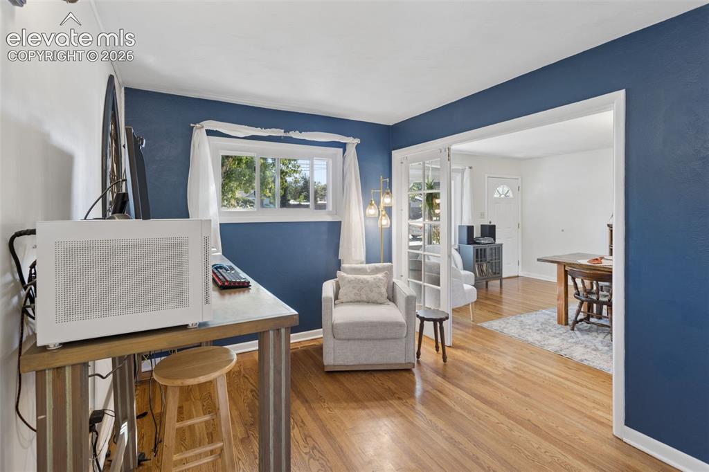 Image 18 of 50: Hardwood flooring, French doors, white trim, and a multi-pane window