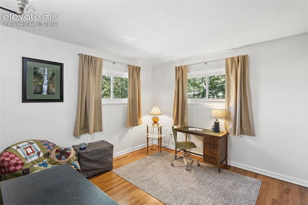 Image 23 of 50: Hardwood-finish flooring, white walls, and two windows