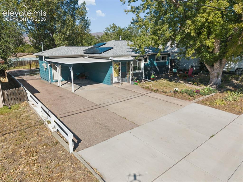 Image 3 of 50: Single-story residence with a covered carport, solar panels, and a concrete