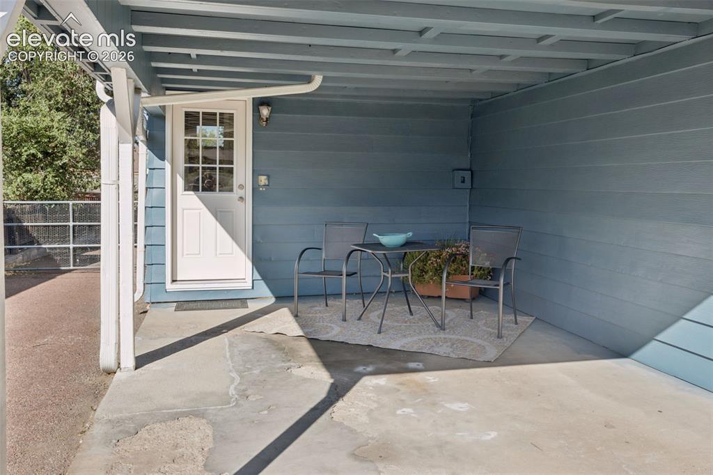 Image 43 of 50: Covered concrete patio with painted siding, a white paneled door with glass