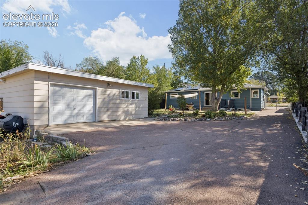 Image 47 of 50: Detached garage with horizontal siding, a paneled overhead door, and multip
