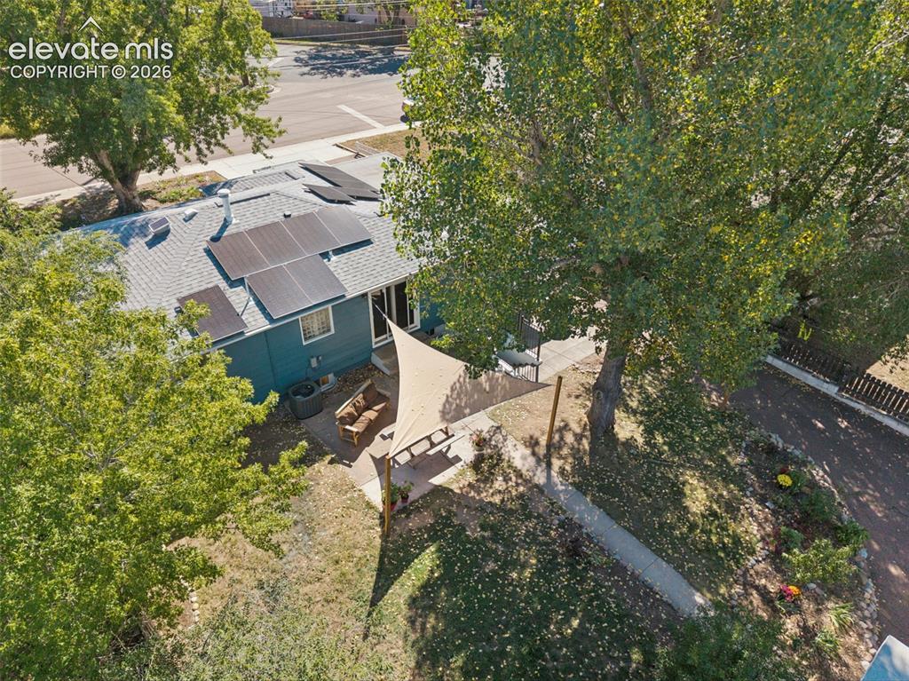 Image 6 of 50: Property exterior featuring a gray shingle roof, solar panels, and mature t