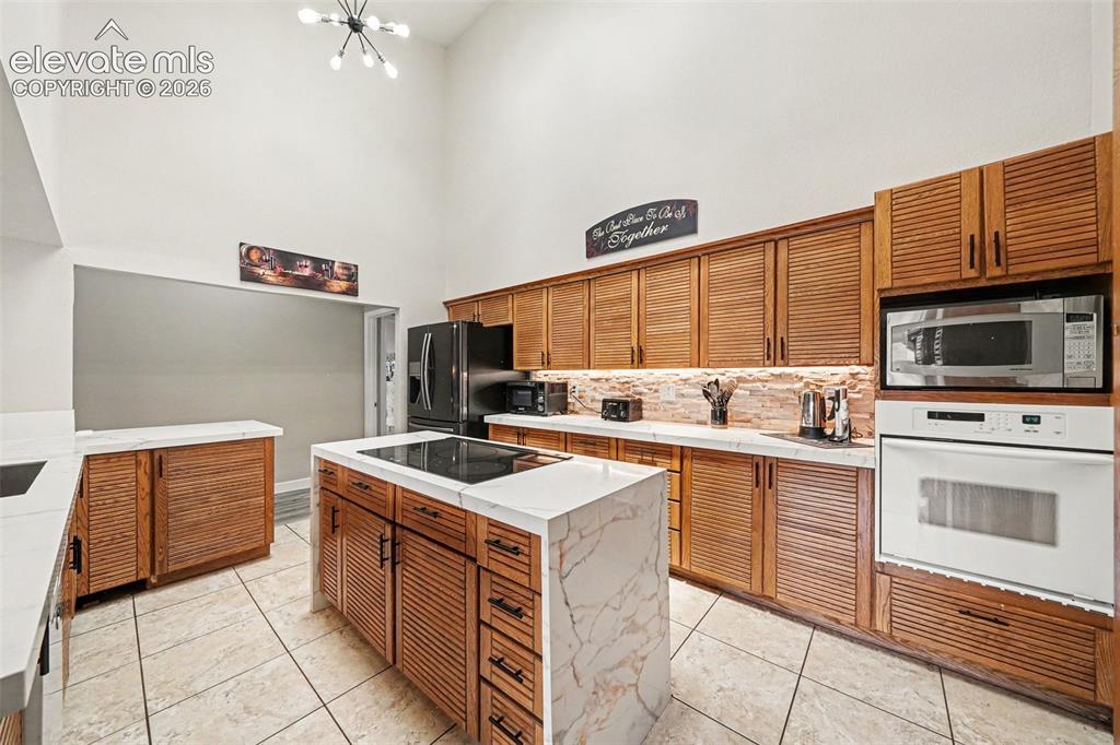 Image 10 of 31: Chefs Kitchen featuring soaring ceilings, wood louvered cabinetry, a built-