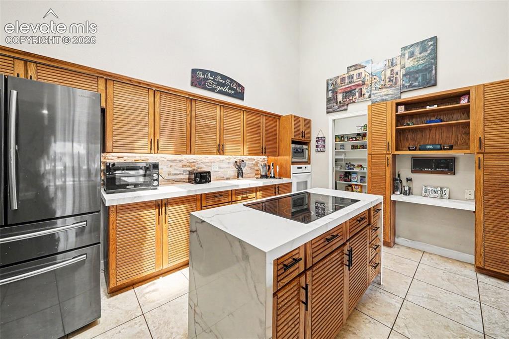 Image 11 of 31: Expansive kitchen featuring a large central island with a built-in inductio