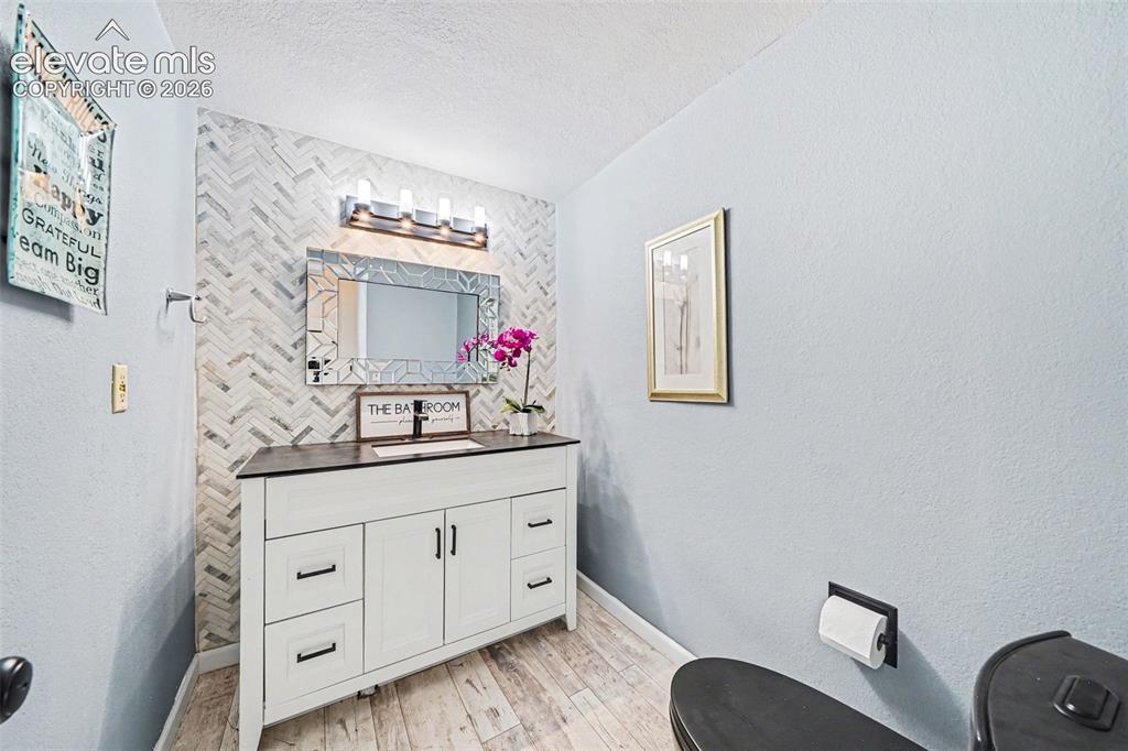 Image 13 of 31: Remodeled guest bath with a dark granite surface countertop and a wall-moun