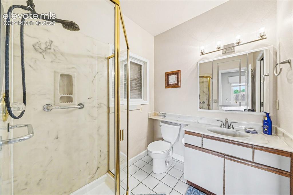 Image 18 of 31: Bathroom featuring a shower with gold-tone framed glass enclosure, a vanity