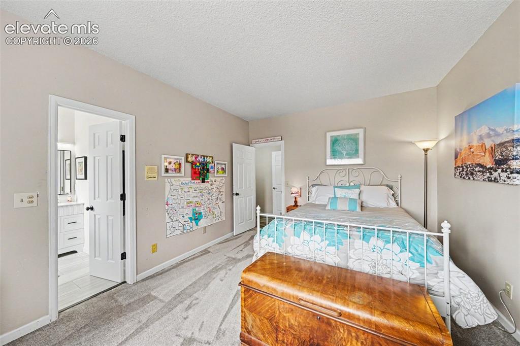 Image 19 of 31: Spacious bedroom with a white panel door opening to a newly remodeled bathr