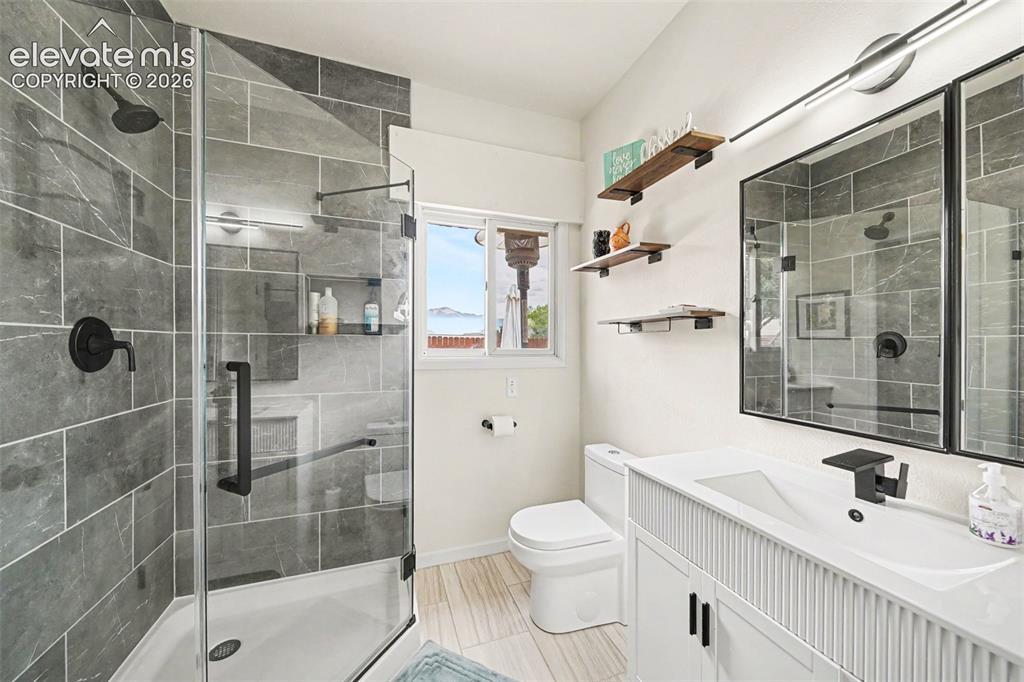 Image 20 of 31: Modern updated bathroom featuring a glass-enclosed shower with gray tile su