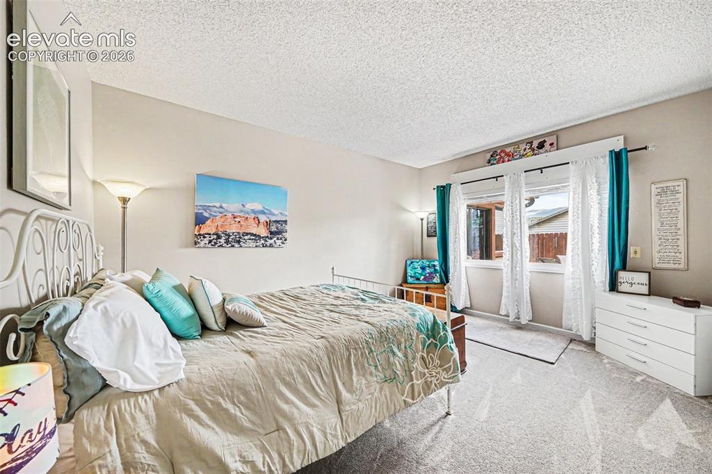 Image 21 of 31: Generously sized bedroom with neutral wall tones and a textured ceiling and