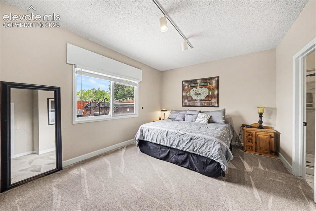 Image 22 of 31: Spacious carpeted bedroom with a large window and its own adjoining bathroo