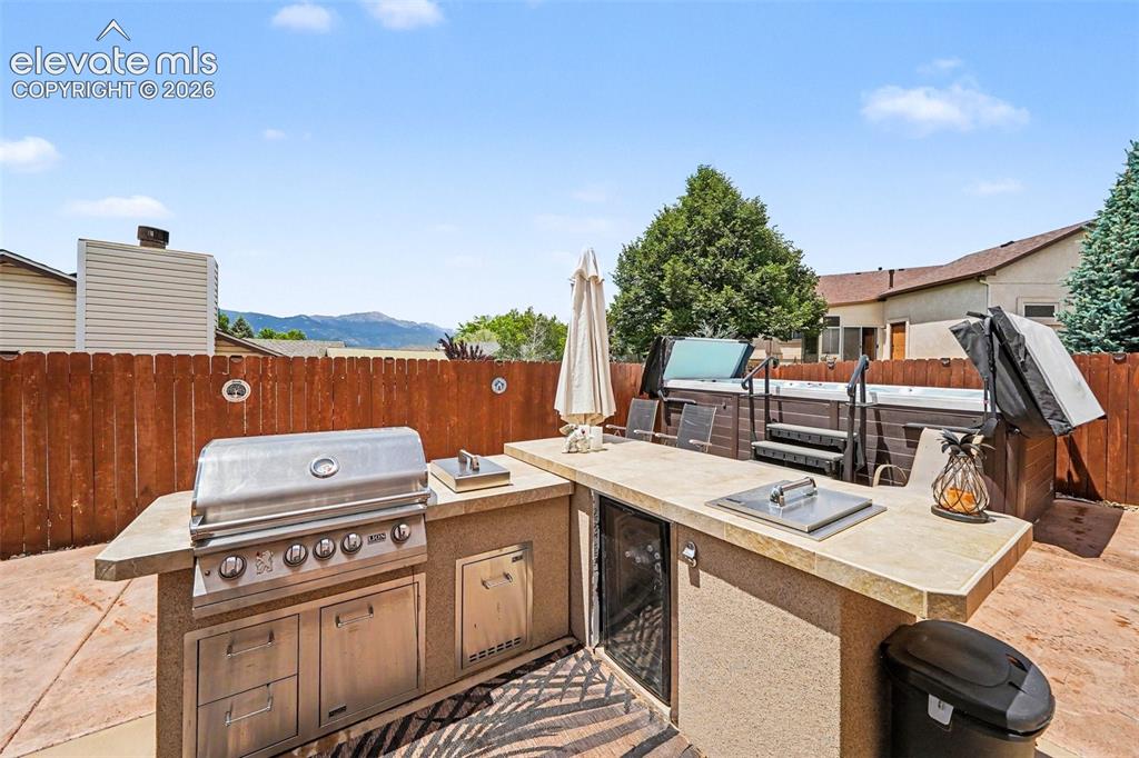 Image 27 of 31: Outdoor kitchen featuring a built-in stainless steel grill, integrated cook