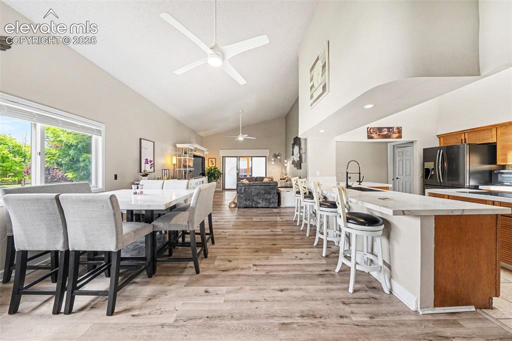 Image 6 of 31: Vaulted ceilings with ceiling fans, engineered wood flooring, a kitchen isl