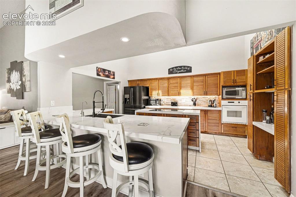 Image 9 of 31: Kitchen featuring wood-finish cabinetry, built-in microwave, wall oven, and