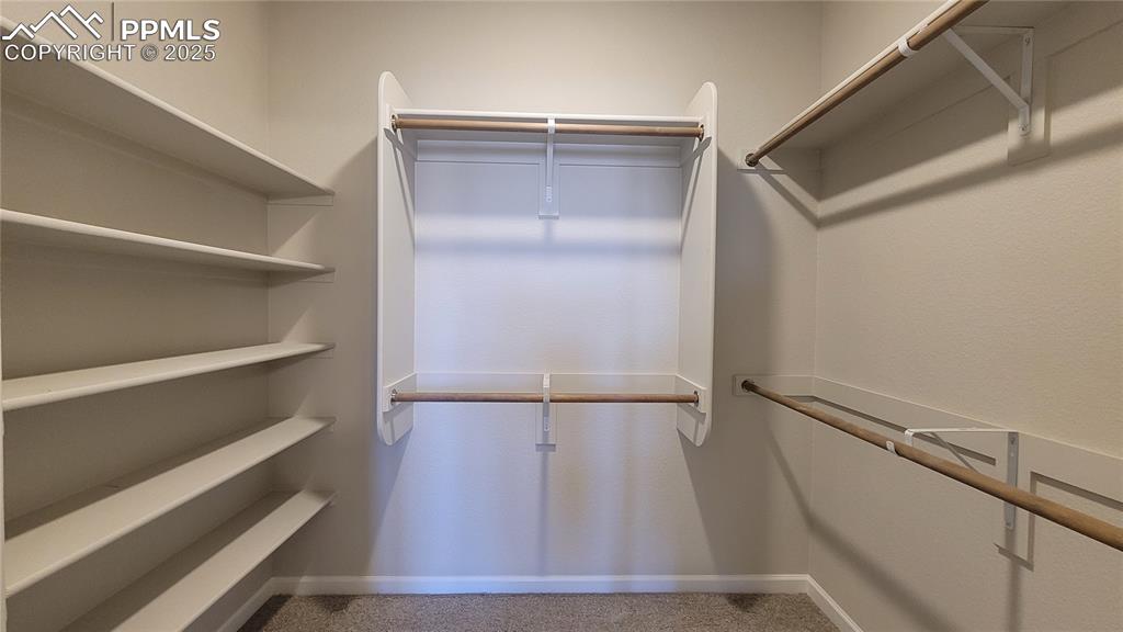 Image 20 of 36: Primary closet with wood shelving and rods!