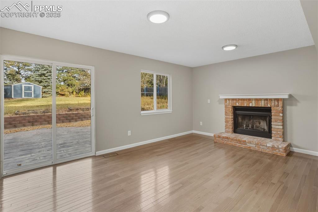 Image 16 of 32: Solid hardwood flooring, family room with wood burning fireplace.