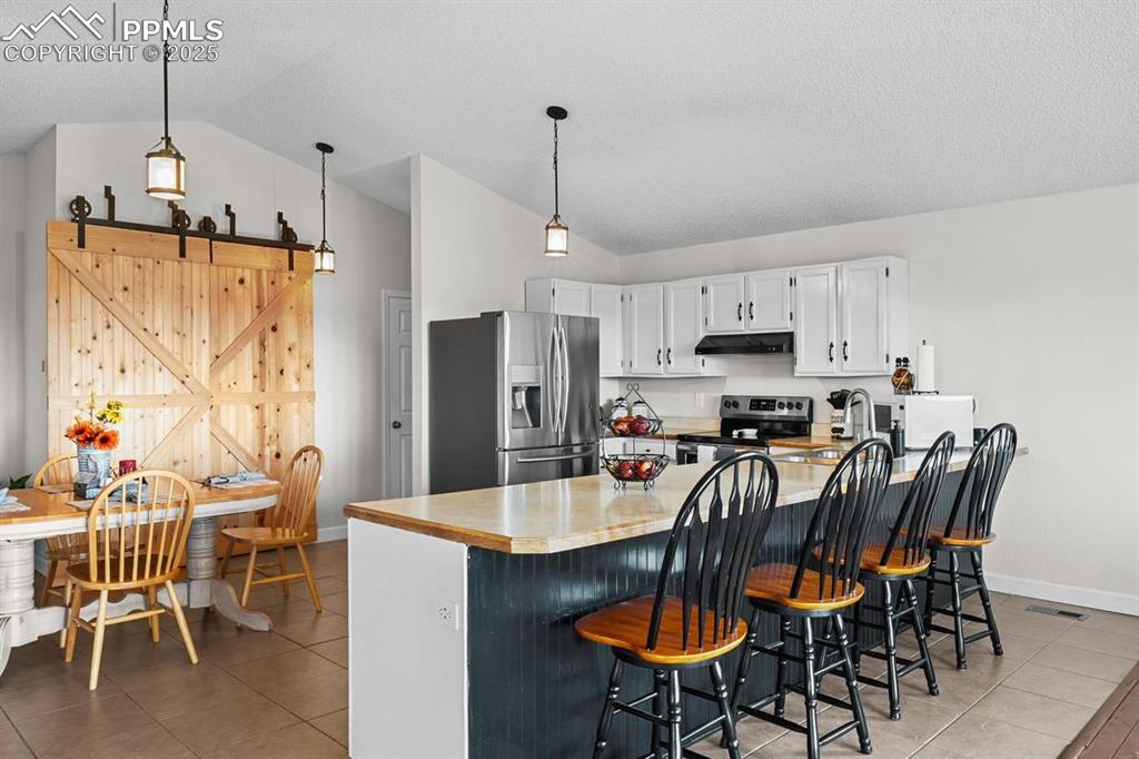 Image 2 of 39: Kitchen featuring stainless steel appliances, pendant lighting, a breakfast