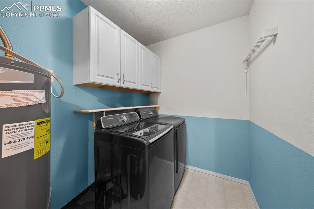 Image 27 of 39: Laundry room featuring water heater and cabinet space