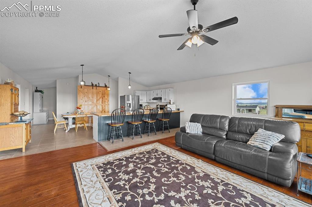 Image 3 of 39: Living area featuring vaulted ceiling, a barn door, hardwood flooring, and 