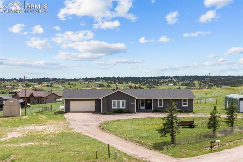 Image 34 of 39: Ranch-style house featuring dirt driveway, two storage shed, a detached gar