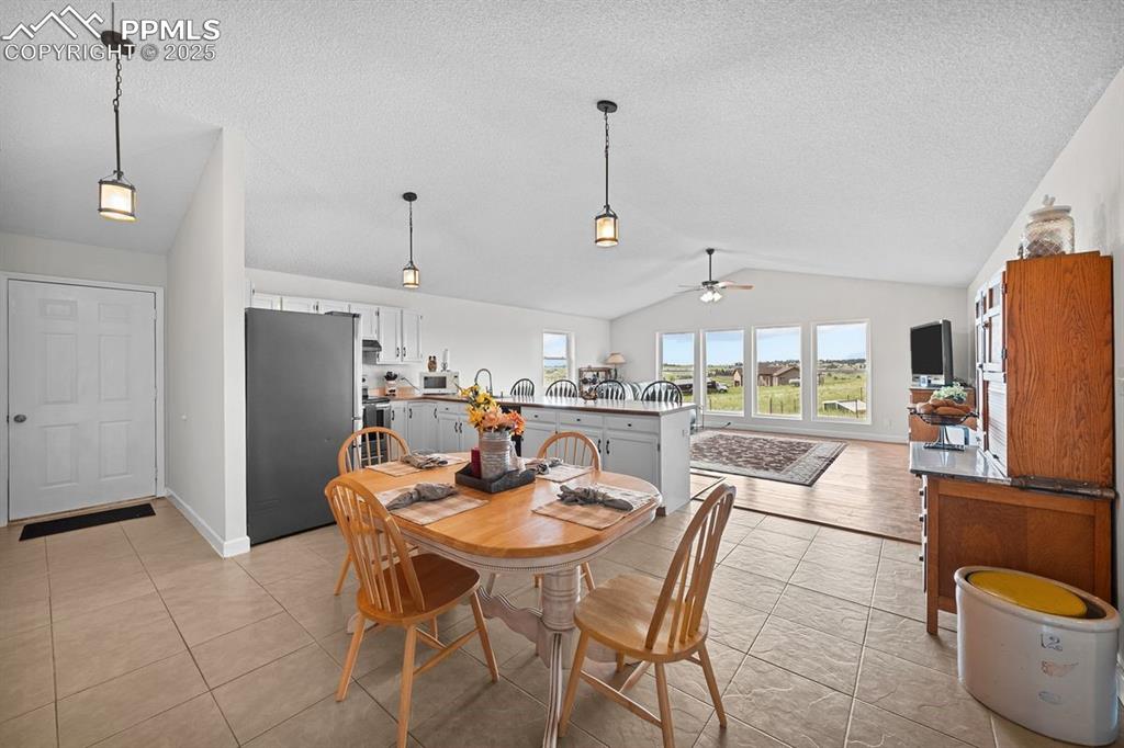 Image 8 of 39: Dining space featuring vaulted ceiling, a ceiling fan and tile floors