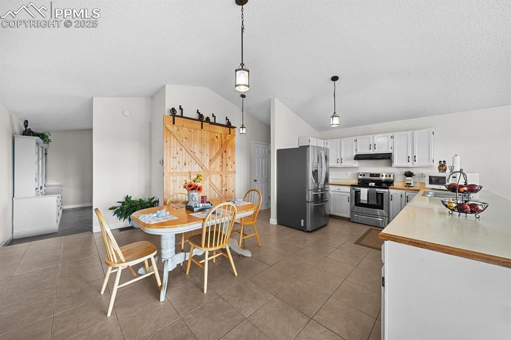 Image 9 of 39: Kitchen with a barn door, light countertops, appliances with stainless stee