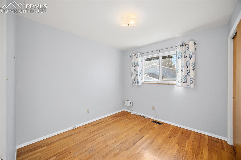 Image 15 of 48: Upper level bedroom with orginal hardwood flooring. 