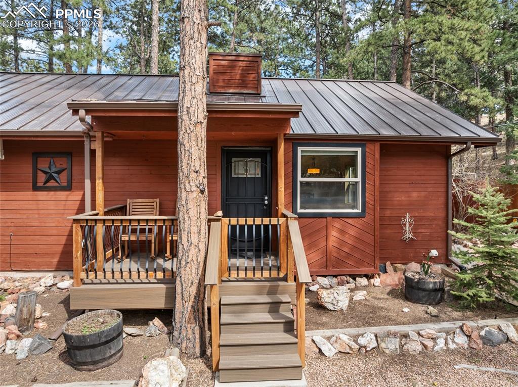 Image 5 of 44: Red-sided exterior featuring a front porch with a wood railing and composit