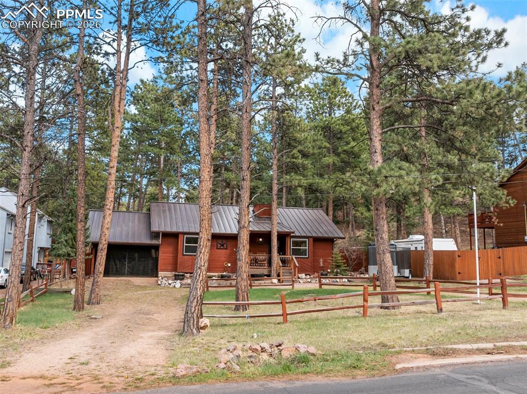 Image 6 of 44: Red-sided residence featuring a dark metal roof and an attached garage with
