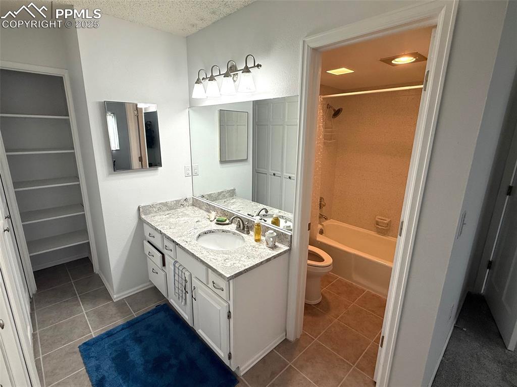 Image 10 of 11: Bathroom with tile floors, vanity, shower combination