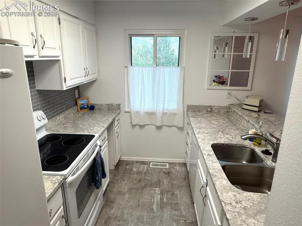 Image 6 of 11: Kitchen featuring white appliances, white cabinetry and granite countertops