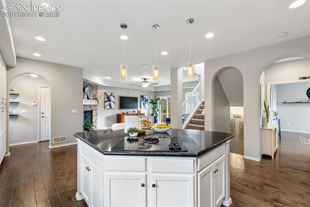 Image 10 of 50: Kitchen featuring arched walkways, white cabinetry, dark stone countertops,