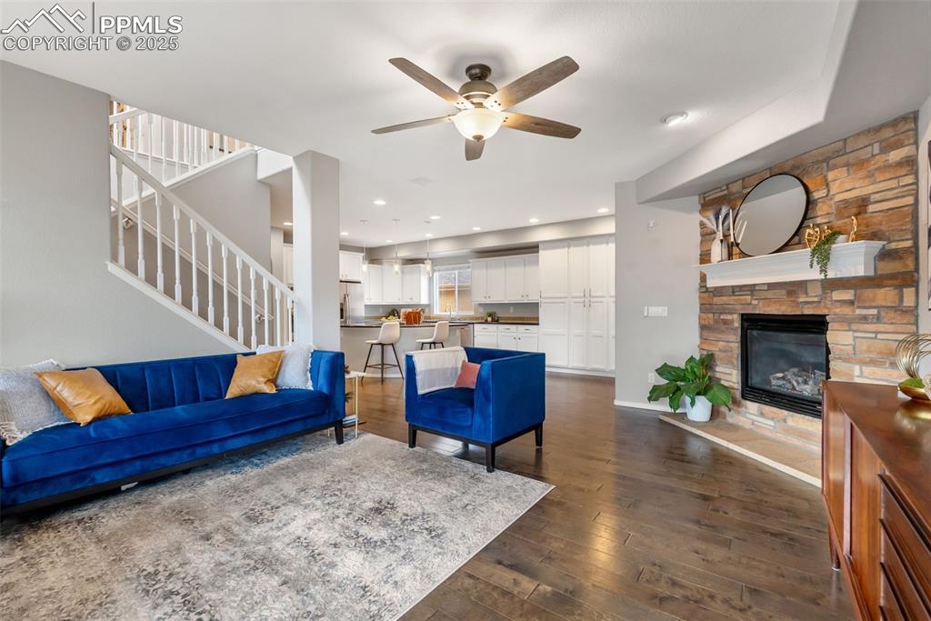 Image 14 of 50: Living room featuring stairs, dark wood-style flooring, a ceiling fan, and