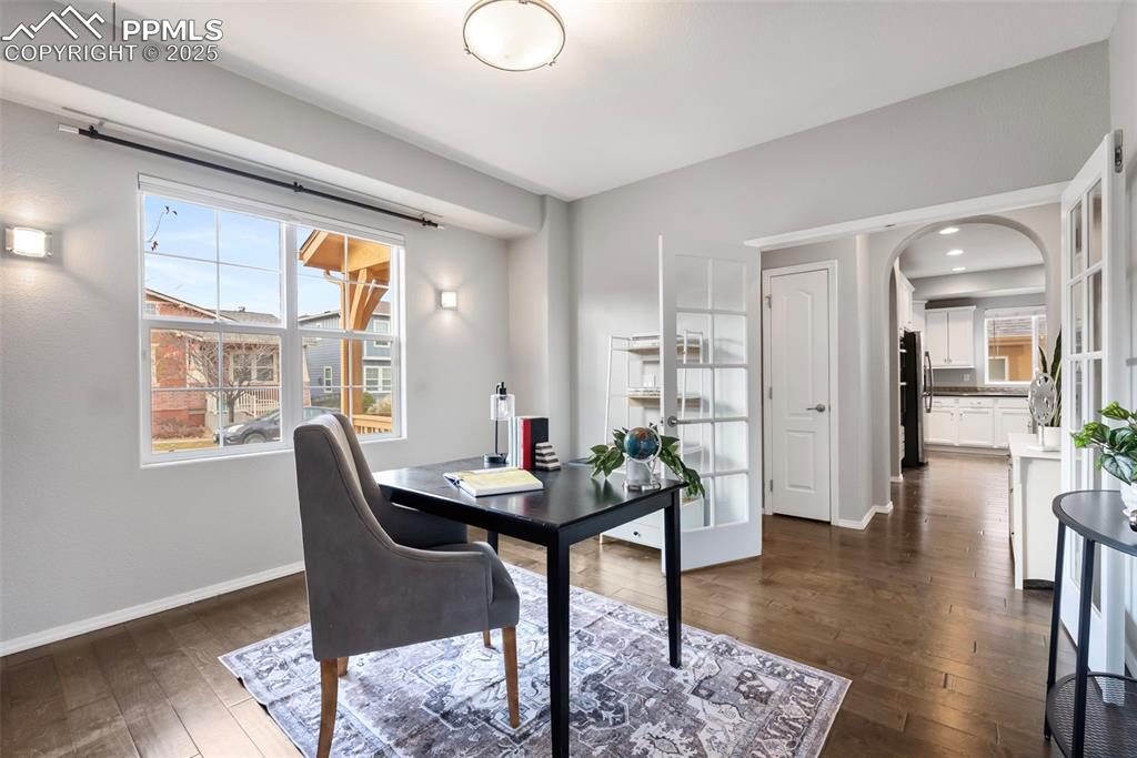 Image 16 of 50: Office area featuring dark wood-style flooring and arched walkways