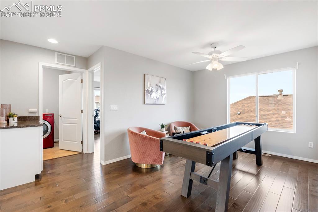 Image 20 of 50: Game room featuring dark wood-type flooring, ceiling fan, and washer / clot