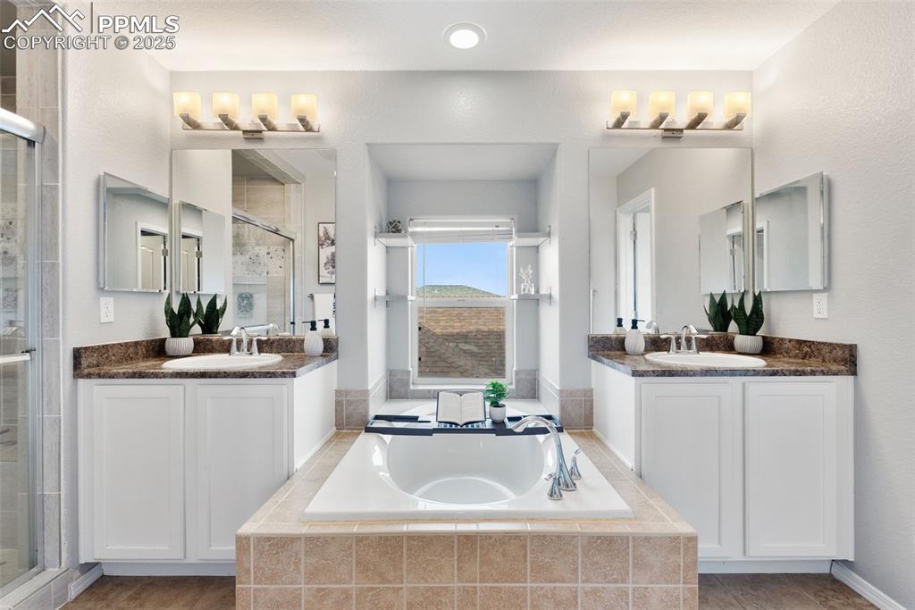 Image 23 of 50: Full bathroom with a bath, a stall shower, and two vanities
