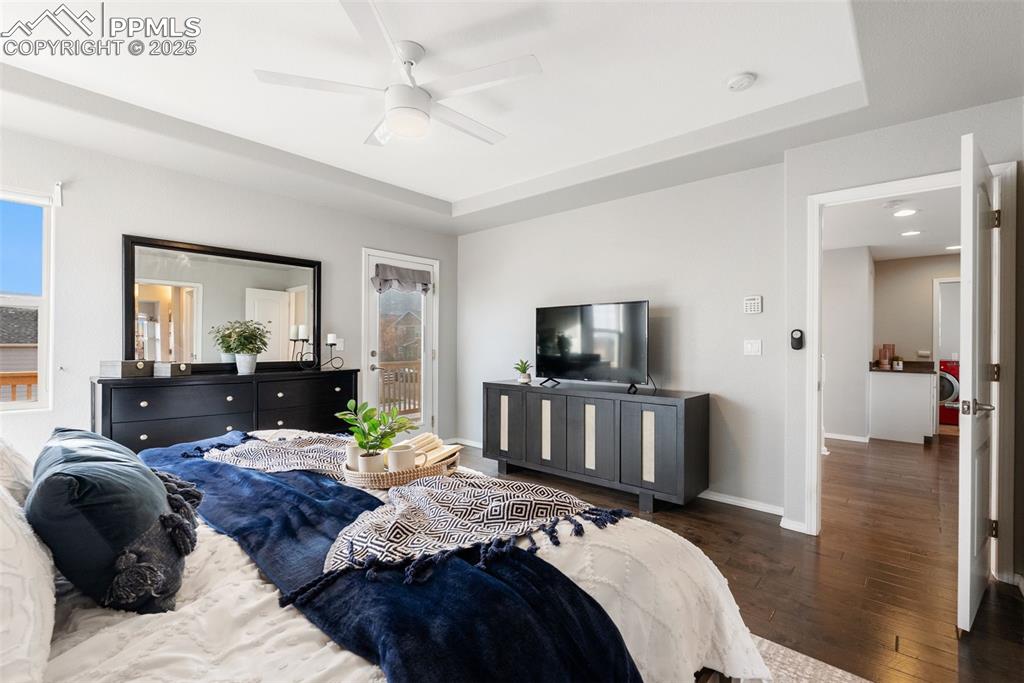 Image 26 of 50: Bedroom featuring access to outside, a tray ceiling, wood-type flooring, an