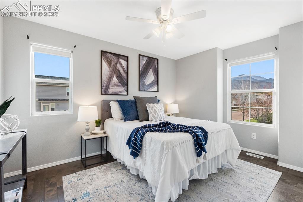 Image 29 of 50: Bedroom with multiple windows, dark wood-style floors, and a ceiling fan